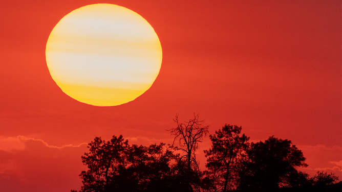 FILE - The sun sets behind smoke from a distant wildfire as drought conditions worsen on July 12, 2021 near Glennville, California.