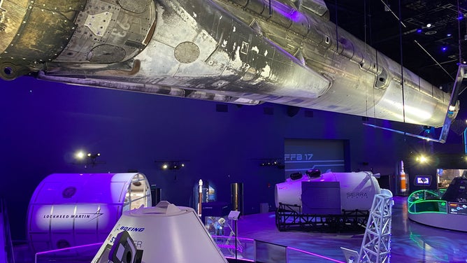 A SpaceX Falcon 9 rocket booster is suspended from the ceiling at Kennedy Space Center Visitor Complex's new "Gateway: The Deep Space Launch Complex" interactive exhibit. (Image: Emilee Speck/FOX Weather)