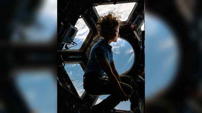 NASA Astronaut Kayla Barron looks at Earth through the cupola windows on the International Space Station.