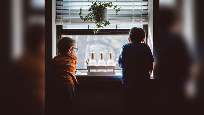 Two boys look out of a window.