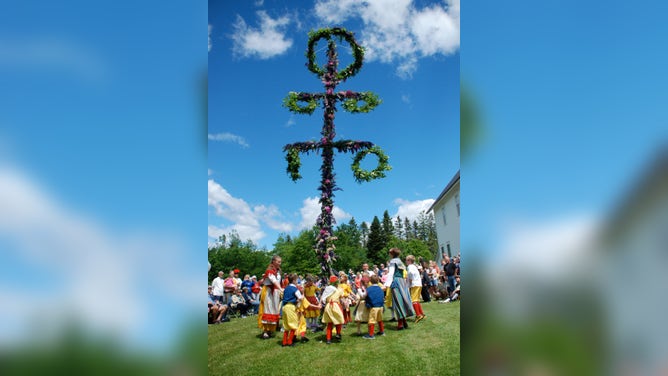 People dance around the Midsommar pole.