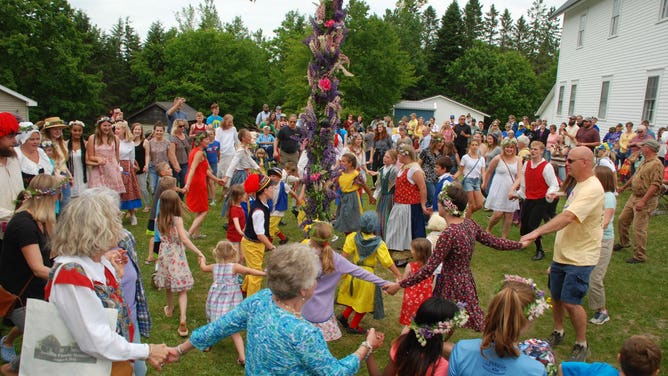 Festival-goers dance around the centerpiece of Midsommar Festival, the Midsommar Pole.