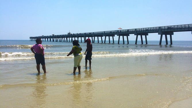 FILE - Two women and a man wading in the ocean at Jacksonville Beach, Florida, USA on July 22, 2015.