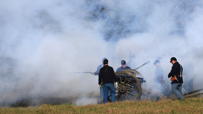 Smoke shrouds soldiers around a cannon.