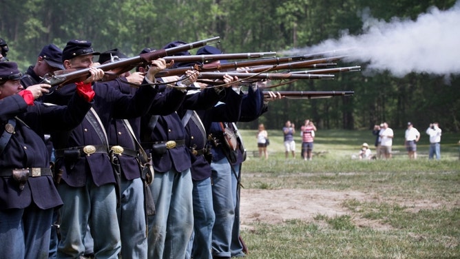 Soldiers fire their arms during a Civil War reenactment.