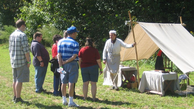 A Revolutionary War reenactor teaches visitors.