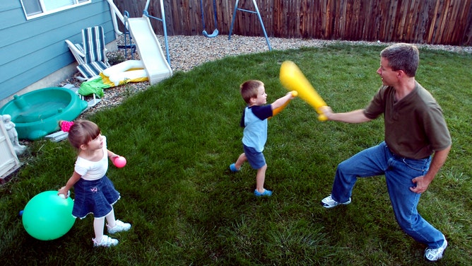 Children play with their father in their backyard.