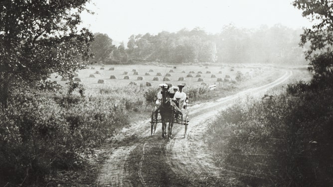 Women riding a horse and buggy down a country road in Wisconsin in 1906.