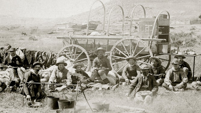 Cowboys sit down for dinner in Wyoming, circa 1890.