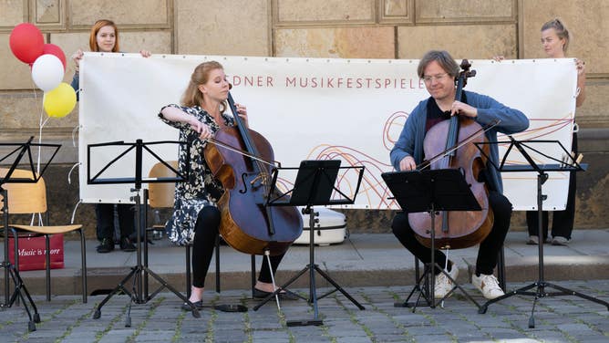 Harriet Krijgh (l), cellist, and Jan Vogler, cellist and artistic director of the Dresden Music Festival, play a cello during a flash mob on Augustusstrasse in Germany.