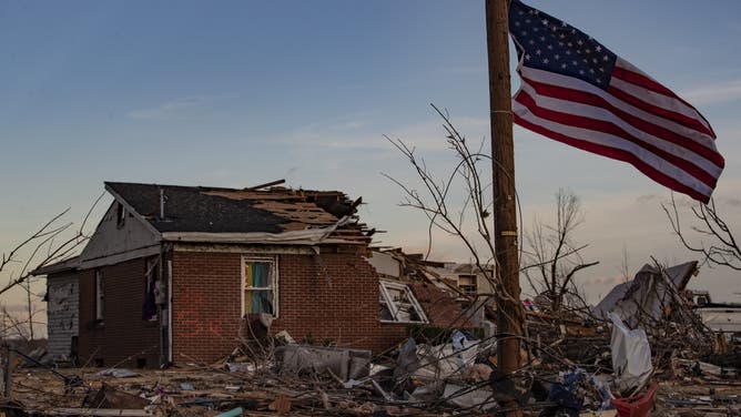 American flag flies in front of a home destroyed by a tornado in Mayfield Kentucky in December 2021.