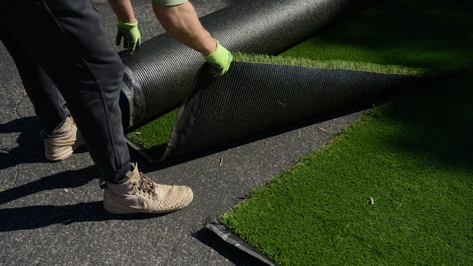A worker installs artificial turf in the front yard of a home in Henderson, Nevada, on Wednesday, March 16, 2022.