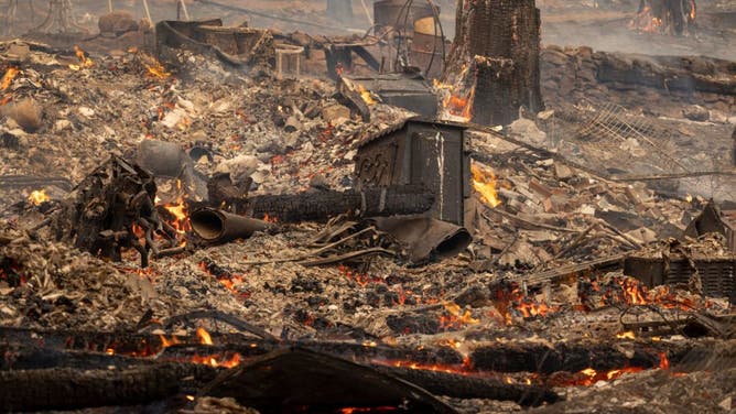 The ruins of a home destroyed in the Oak Fire smolder near Midpines, northeast of Mariposa, California, on July 23, 2022.