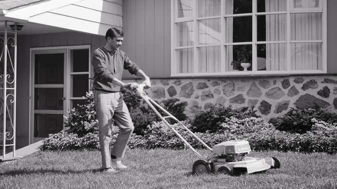 A 1960s man mows his lawn with a rotary gasoline mower.
