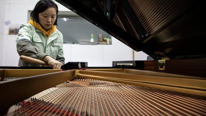 A woman tunes a piano.