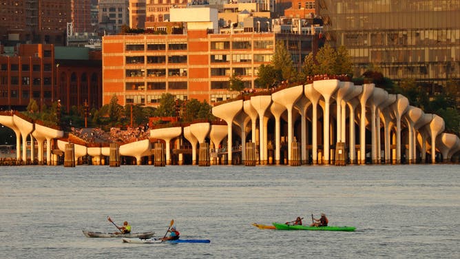 People paddle their kayaks in the Hudson River in front of Little Island as the sun sets in New York City on June 20, 2022, as seen from Hoboken, New Jersey. (Photo by Gary Hershorn/Getty Images)