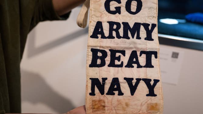 Cassandra Hatton, Senior Vice President, holds Buzz Aldrin's hand stitched 'Go Army, Beat Navy' exposed to the space atmosphere during Aldrin's Gemini XII spacewalks on display during a press preview at Sotheby's on July 21, 2022 in New York City