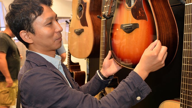 Yoshihiko Tanbara inspects guitars hanging on display.