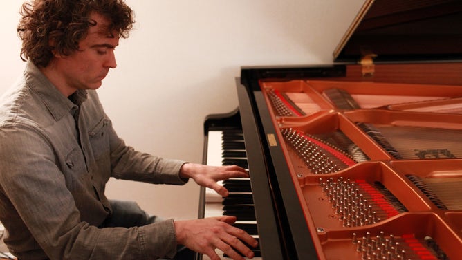 Paul Lewis plays his piano during a portrait session.