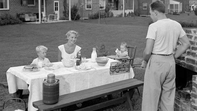 A family hosts a cookout on their well-kempt lawn.