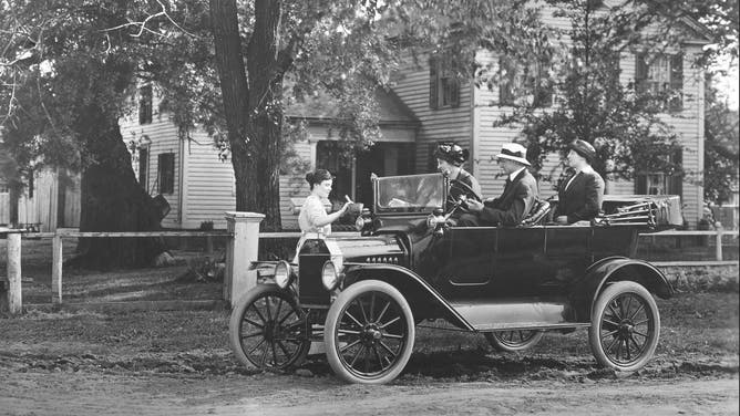 A Ford Model T parked next to a home in 1908.