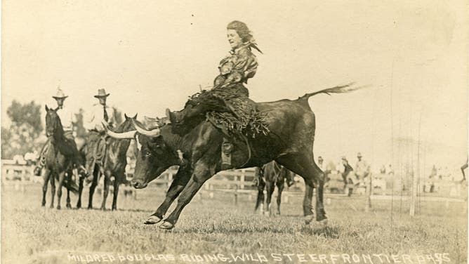 Mildred Douglas rides a bull.