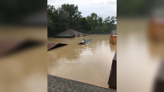 A woman and her dog wait on a neighbors rooftop for rescue in Letcher County, Kentucky from flooding.