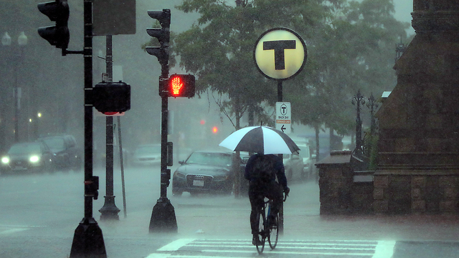 FILE - A brave cyclist rides up Boylston Street during a thunder and rain storm near Copley Square in Boston on July 23, 2020.
