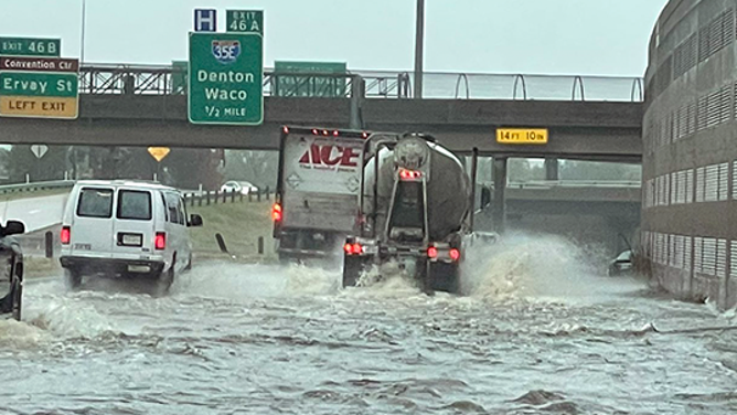 Vehicles are seen driving over a water-covered highway in Dallas on Monday, Aug. 23.