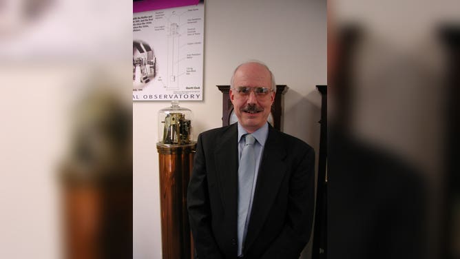 Dennis McCarthy, in the early 2000s when he was the Director of the Directorate of Time, standing in front of the pendulum clock, which was the world’s most precise clock from the 1920s until World War II. 