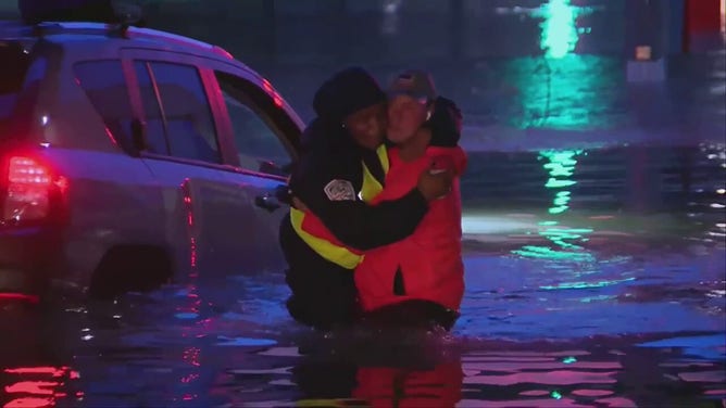 FOX Weather multimedia journalist Robert Ray is seen carrying a woman to safety after she drove onto a water-covered roadway, which submerged her vehicle.