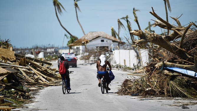 Residents pass damage caused by Hurricane Dorian on September 5, 2019, in Marsh Harbour, Great Abaco Island in the Bahamas.