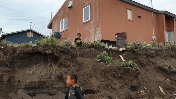 Jeremy Hawley, 3, stands near his uncle's home, which is dangerously close to a place where the permafrost is melting and being eroded away on September 15, 2019 in Kivalina, Alaska. His uncle, Ikey Hank, said 'that about 10 years ago is when he noticed the erosion and is hopeful his home will be moved before it crashes into the lagoon.'