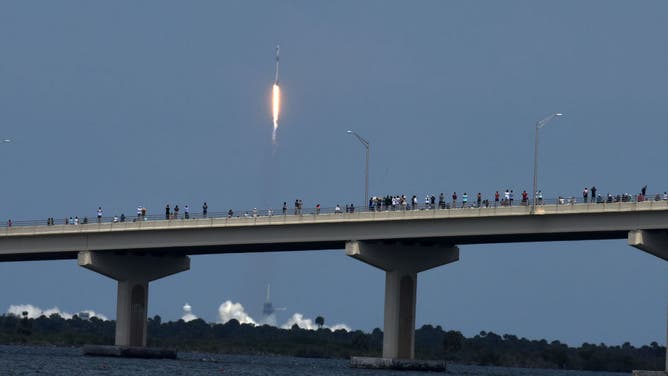 People line the A.Max Brewer Causeway to watch the launch of a SpaceX Falcon 9 rocket from Cape Canaveral, Florida May 30, 2020 in Titusville, Florida . American astronauts Bob Behknen and Doug Hurley are aboard the crew Dragon capsule on a mission to link up with International Space Station. This is NASA's first crewed launch from U.S. soil since 2011 at the ending of the Space Shuttle program.