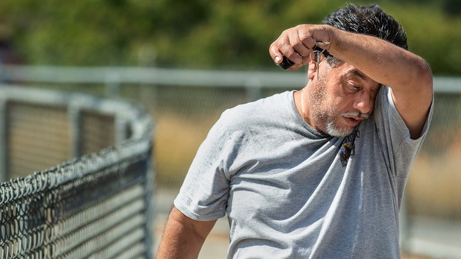 FILE - Miguel Garcia of Tijunga wipes the sweat off of his face after jogging at Hansen Dam Recreation Area in Pacoima.