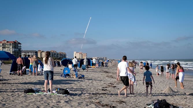 Beachgoers look on as the Atlas V rocket carrying the GOES-T weather satellite launches from Space Launch Complex 41 in Cocoa Beach, Florida, on March 1, 2022.