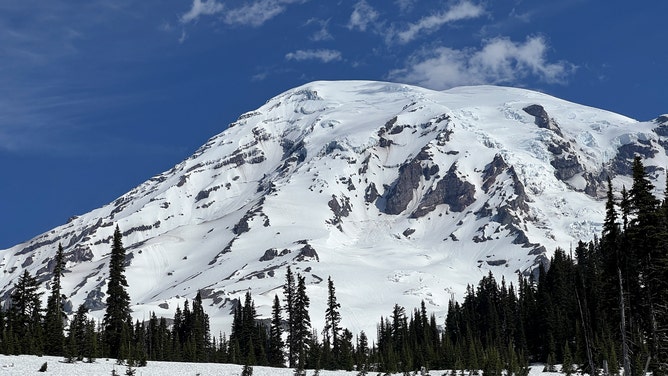 Wisps of clouds hover above a snowy Mt. Rainier in Washington.