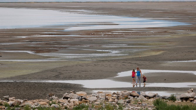 Park visitors walk along a section of the Great Salt Lake that used to be underwater at the Great Salt Lake State Park on Aug. 2, 2021.