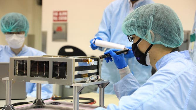 Members of the EQUULEUS (EQUilibriUm Lunar-Earth point 6U Spacecraft) team prepare their CubeSat to be loaded in the Space Launch System’s Orion stage adapter for launch on the Artemis I mission.