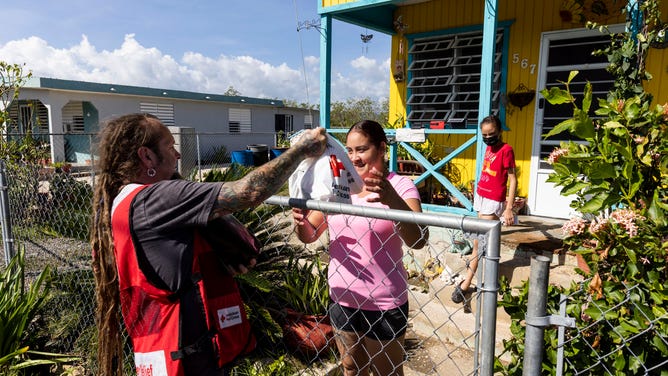 September 24, 2022. Playita Cortada, Puerto Rico. Red Cross volunteer Chris Berry handing out comfort kits to Carmen Santiago in the Playita Cortada community in Puerto Rico.