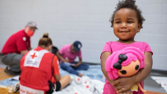 September 27, 2022. Clearwater, Florida Red Cross volunteer Martha Narvaez entertains Serenity, age two, at the Red Cross Evacuation Shelter in Clearwater, Fl.
