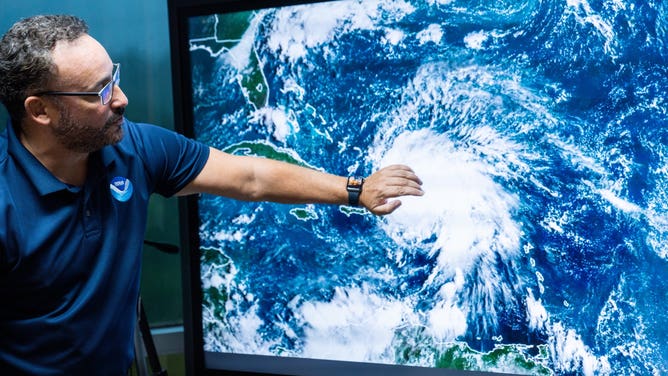 A man motions to a satellite image of Hurricane Fiona over Puerto Rico.