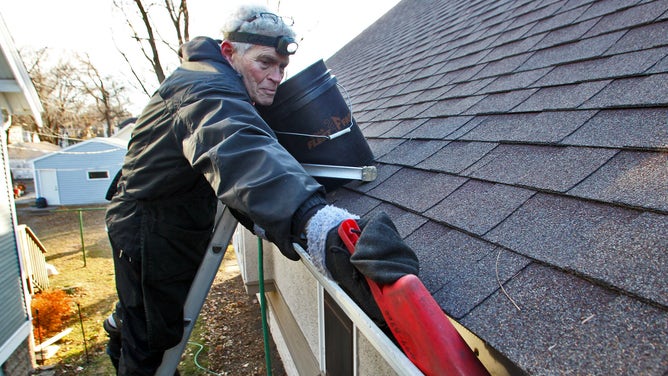 Burton Johnson, a professional gutter cleaner, cleans a home's gutters before a storm.