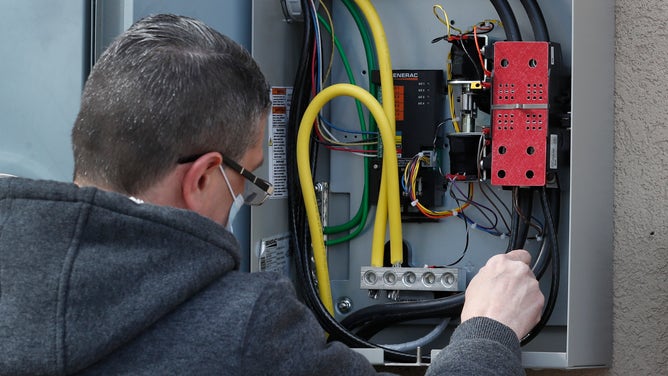 A worker from Captain Electric, inspects a new power box for a 24-kilowatt Generac home generator on February 18, 2021 in Orem, Utah.