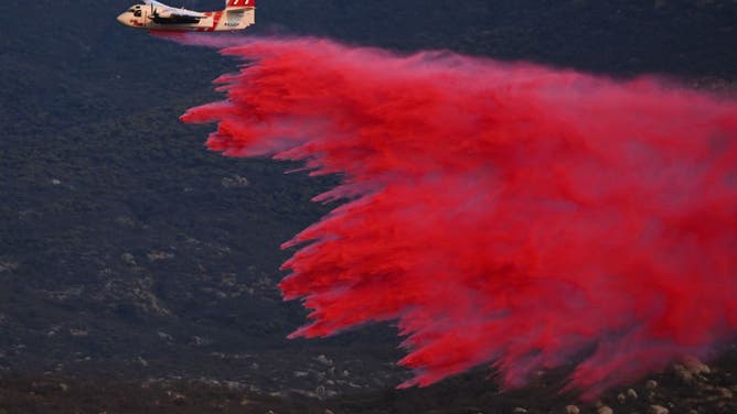 A firefighting aircraft makes a retardant drop as crews work to contain a wildfire as it approaches homes during the Fairview Fire near Hemet, California in Riverside County on September 7, 2022