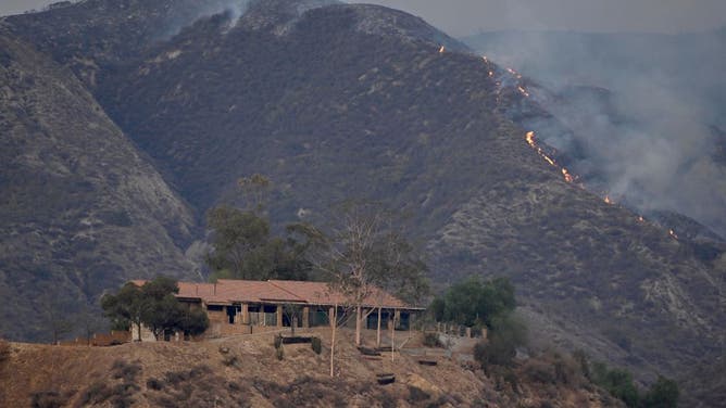 A home sits on a hill as the Fairview fire burns behind it in Hemet on Wednesday, Sept. 7, 2022.