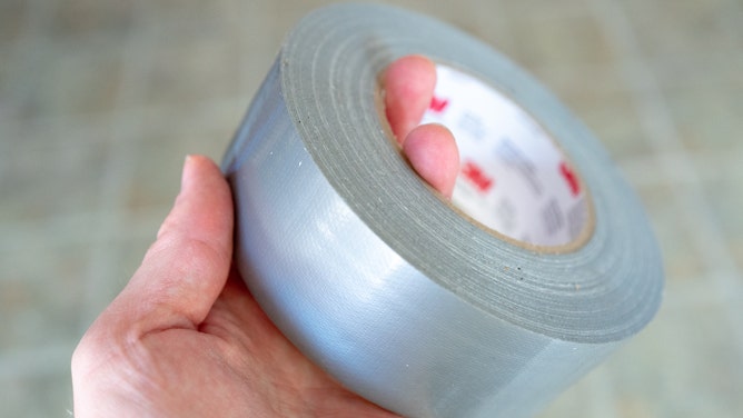 Close-up of hand of man holding roll of duct tape.