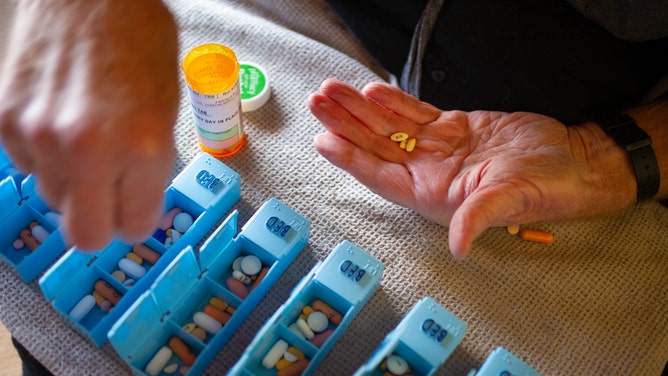 Person with Multiple Sclerosis hand sorting prescription pills.