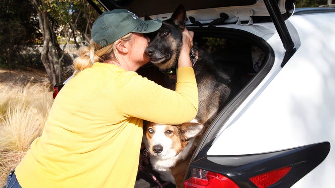 Laura Morales hugs her German shepherd Mia after loading the family pets, including Charlie the corgi, into the car as she and her family prepares to flee their home on Rosewood Drive in Healdsburg, Calif. on Saturday, Oct. 26, 2019 after authorities issued evacuation orders to 50,000 residents of Healdsburg and Windsor.