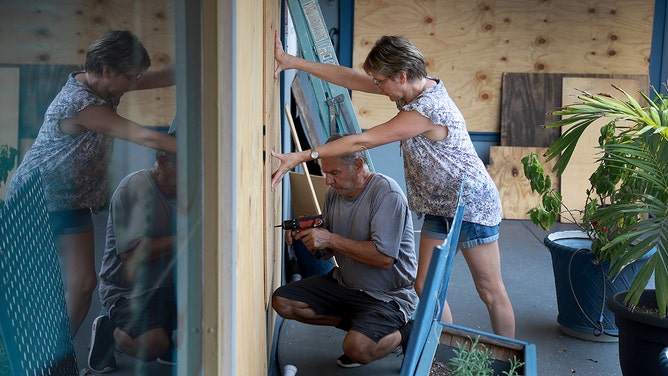 Frederic Herodet and Mary Herodet board up their Gulf Bistro restaurant as they prepare for the possible arrival of Hurricane Ian on September 27, 2022 in St Petersburg Beach, Florida.